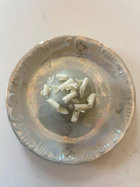 Crumpled white paper or eggshell pieces in the center of a worn, rusty metal bowl on a light surface
