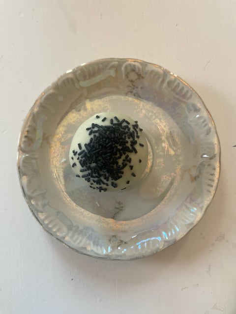 Clear plastic dish with heap of small black seeds in center against white background